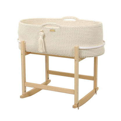 White woven baby crib with natural wood stand on a light gray background