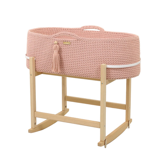 Pink woven bassinet with wooden stand on a white background